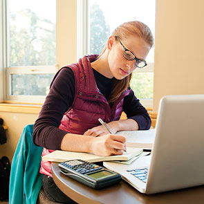 Student working on notebook and laptop. Read about Gifts from Retirement Plans